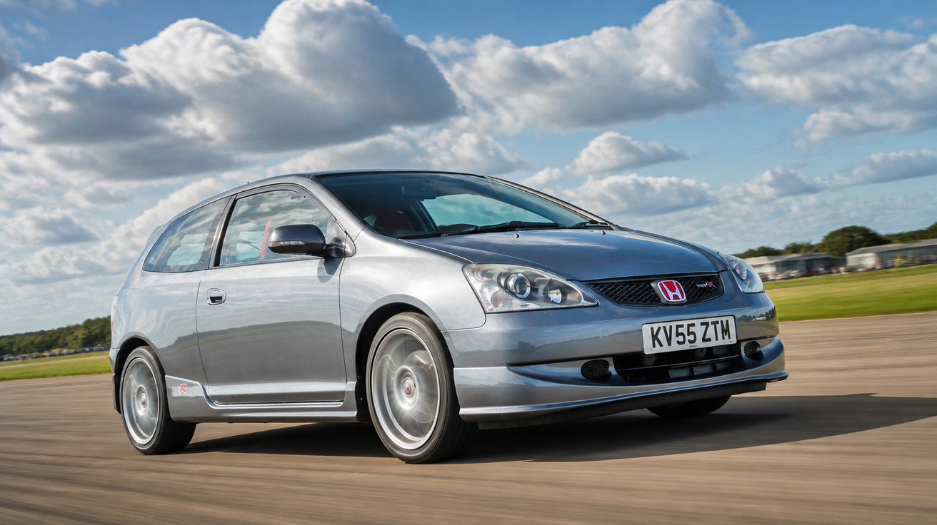 Silberner Honda Civic Type R fährt auf Landstraße bei bewölktem Himmel, dynamische Perspektive.