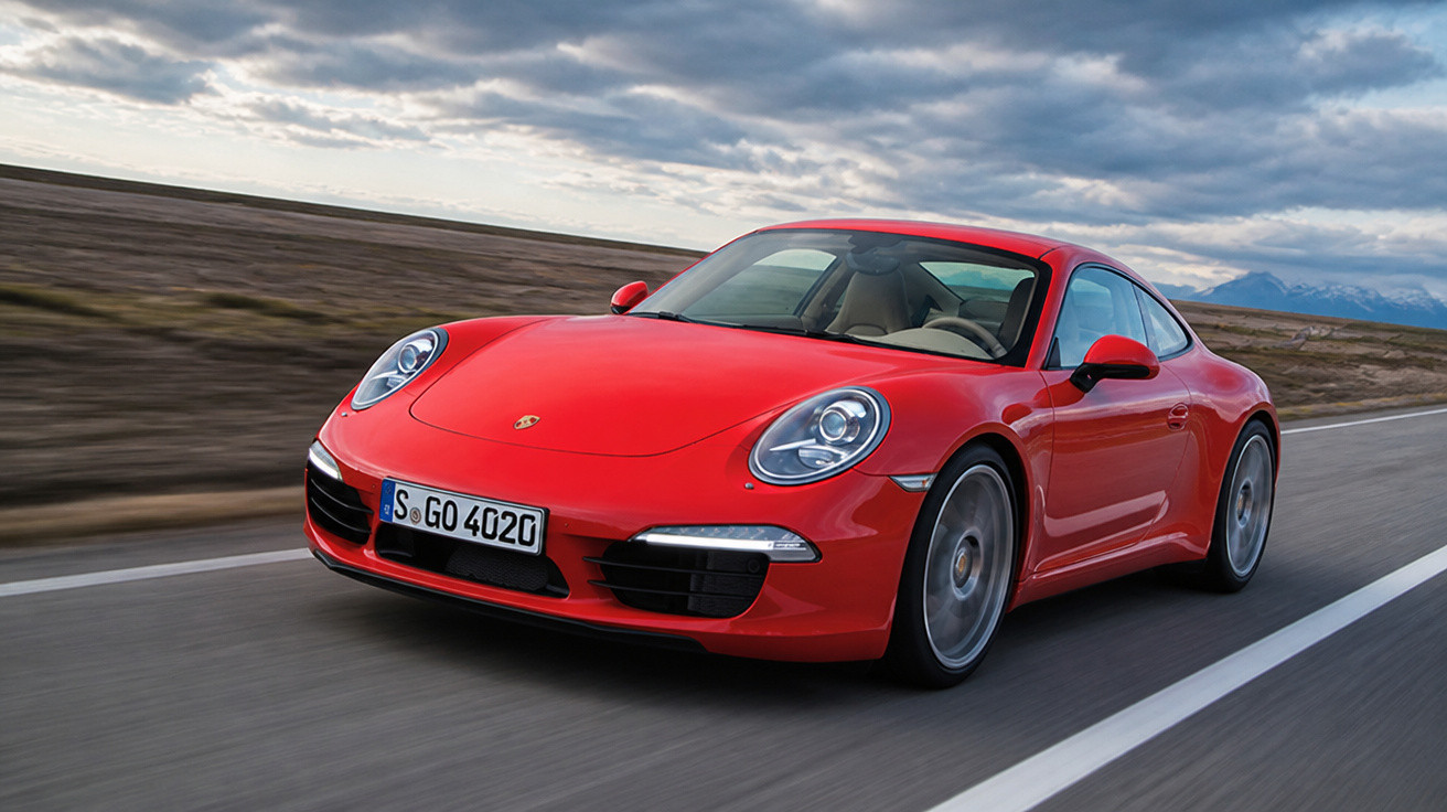 Roter Porsche 911 fährt auf Landstraße bei bewölktem Himmel mit Bergen im Hintergrund.